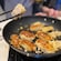 A frying pan containing pieces of fried fish